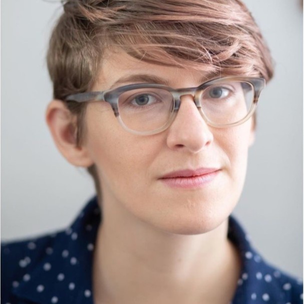 Portrait of Lehua Gray in glasses and a navy polka-dot shirt against a light grey background.